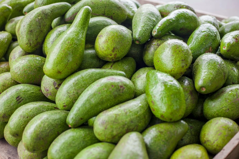 the large pile of fresh avocados is stacked up in boxes