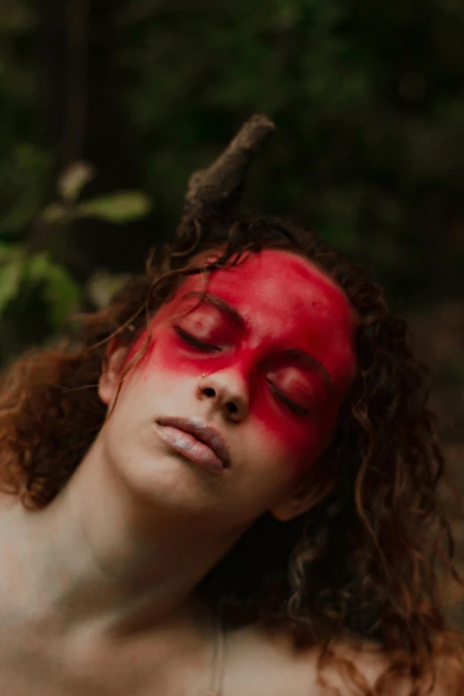 a shirtless woman with red painted face, holding an animal