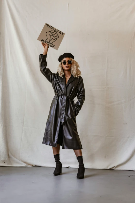 a person wearing sunglasses and a coat holds up a sign