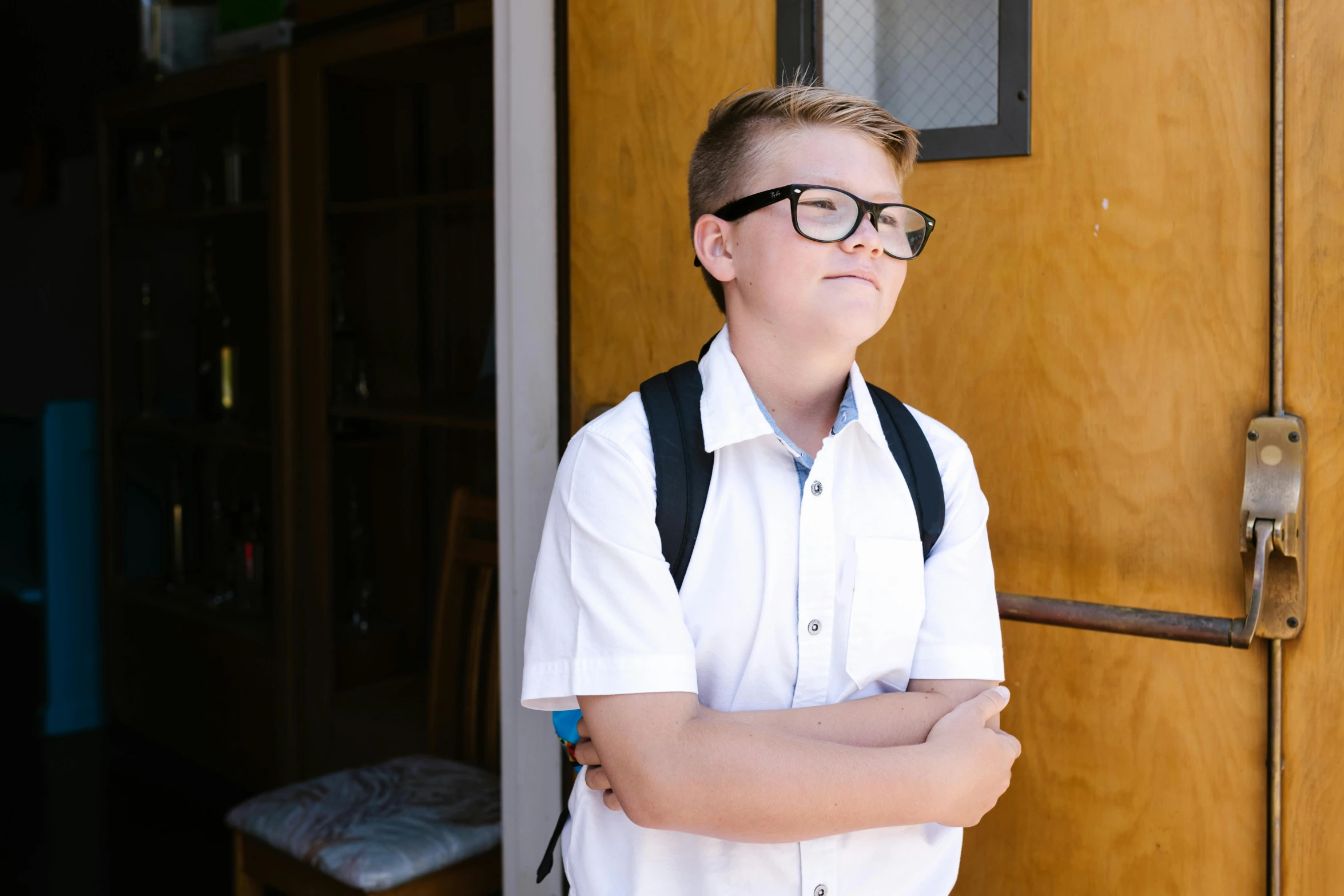 a boy wearing glasses and suspenders and smiling