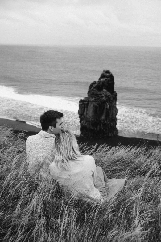 black and white pograph of a young couple sitting on a beach