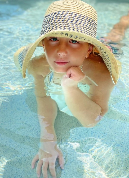 a  wearing a hat swimming in a pool