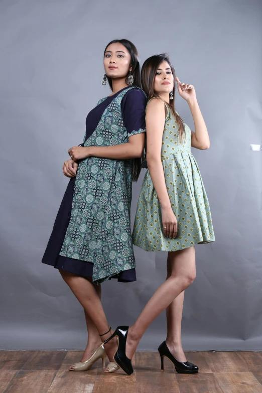 two young ladies posing in a studio with one holding a purse