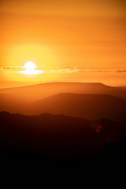 the sun is setting over hills and mountains