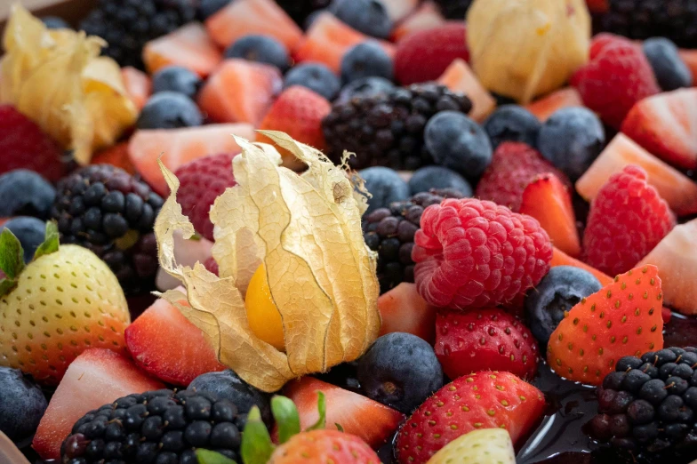 a variety of fruit, with golden leaf, has been placed in the middle of a large platter