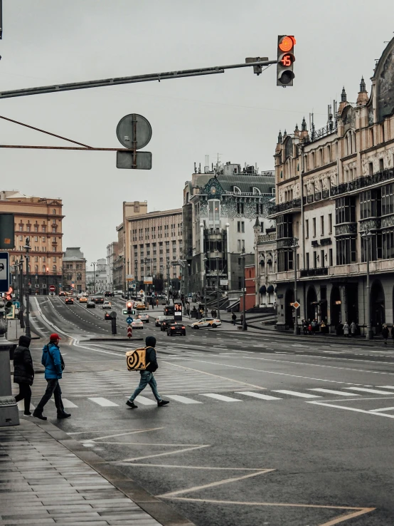 people walking across an intersection with cars and buses