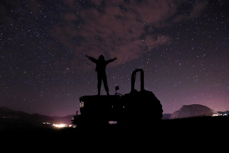 silhouette of a person standing on top of machinery against the night sky