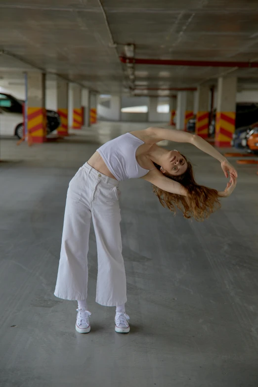 a woman in a parking garage holding her leg up and dancing