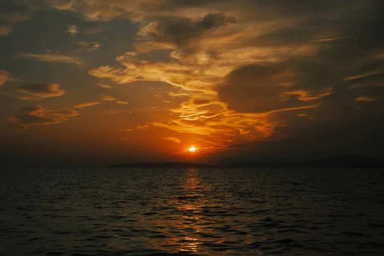 the sun setting over water on a cloudy day