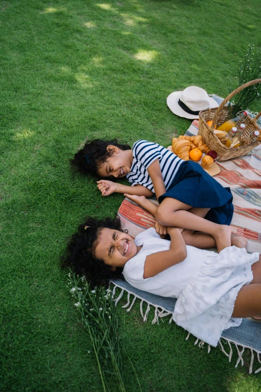 two people lying on the grass and having a picnic