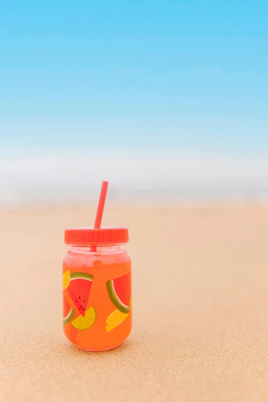 a glass jar with a straw next to it on the beach