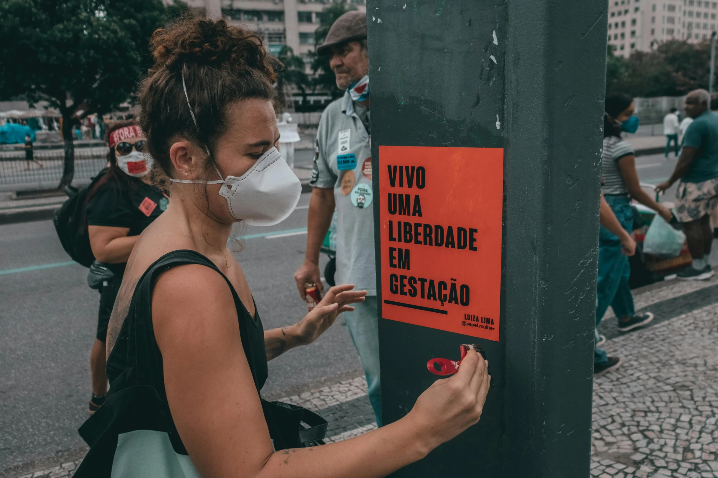 a woman standing by a pole with a face mask