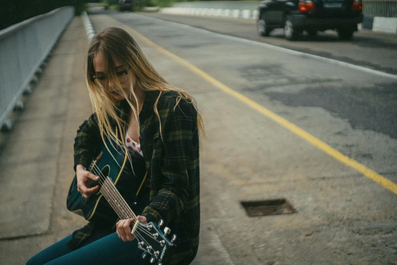 a young woman sitting on top of a cement bench with a guitar