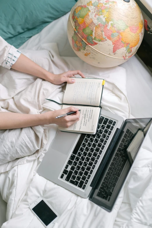 a woman sitting in bed next to a laptop computer