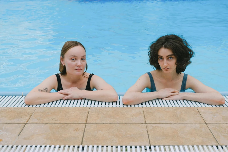 two women wearing black sitting in the middle of a pool