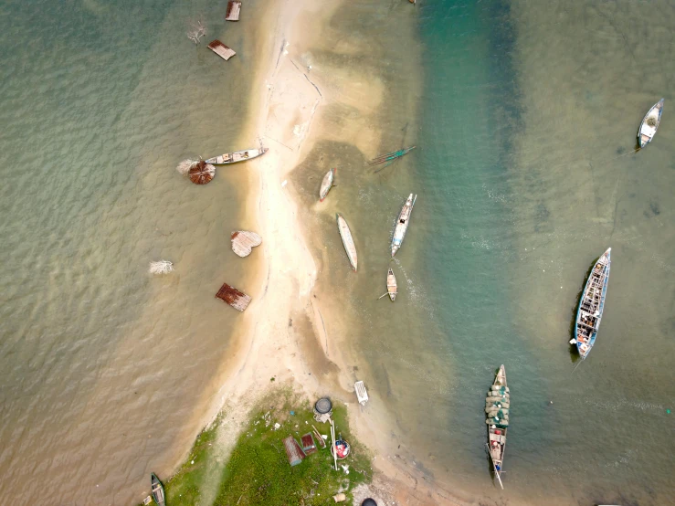 a group of boats floating on top of a lake next to a beach