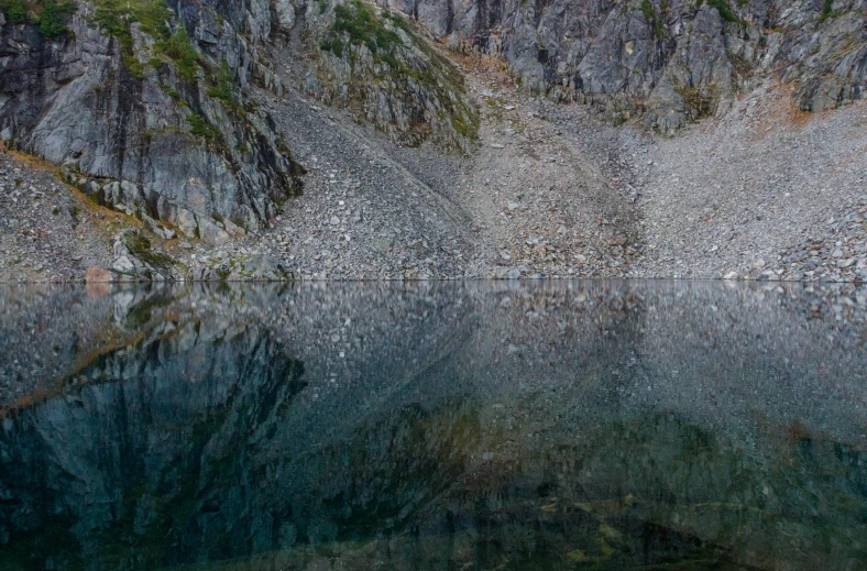 a mountain scene with water and rocks on the side