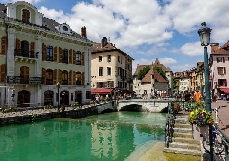 a canal with several people and buildings with green water in the background