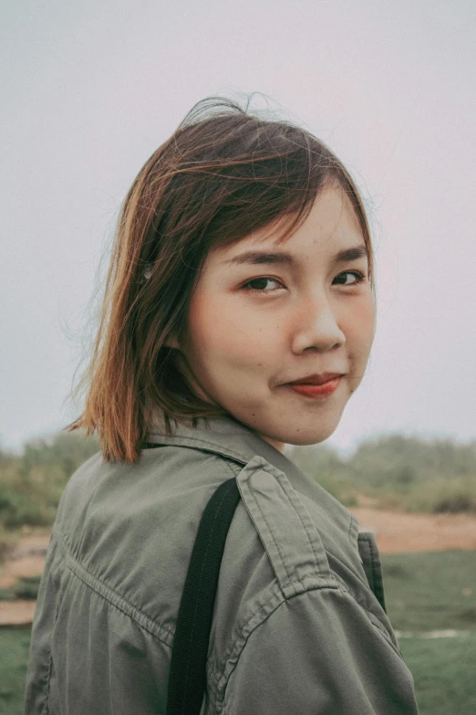 a young woman poses for a portrait on a cloudy day