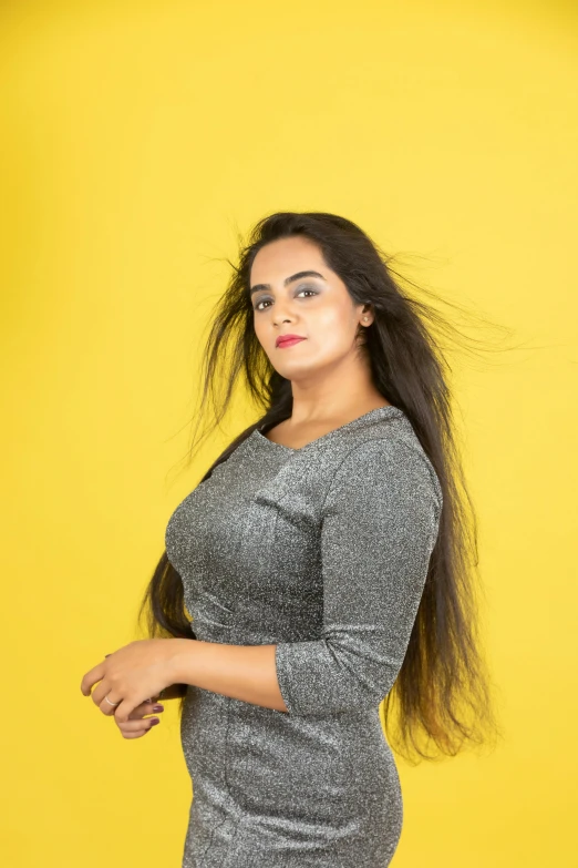 a woman standing in front of a yellow background