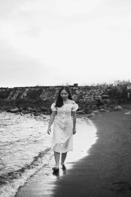 a woman in white dress walking on a beach