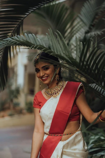 a beautiful indian woman in a sari posing by some plants