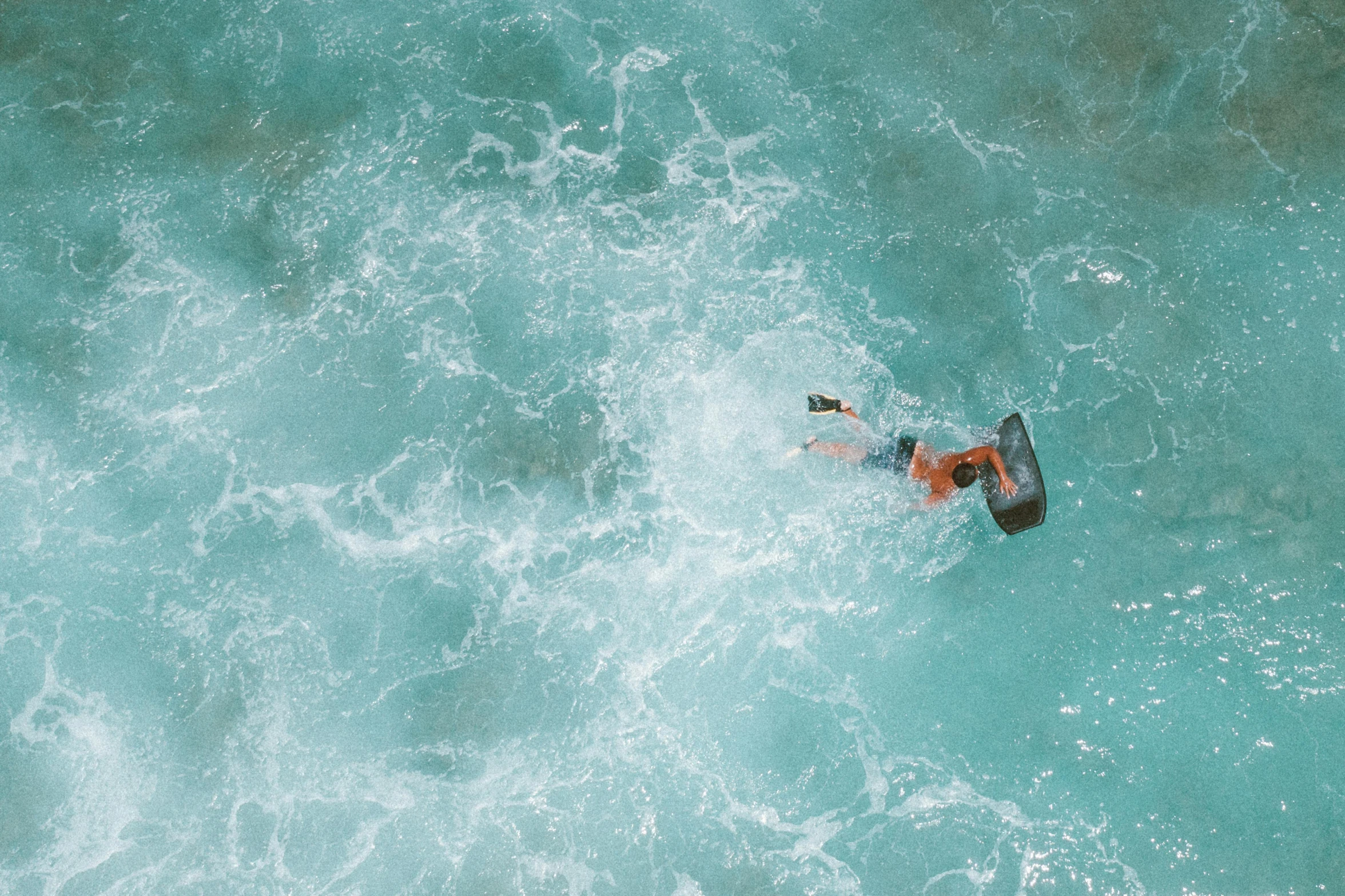 an aerial view shows a person on a surfboard in the water