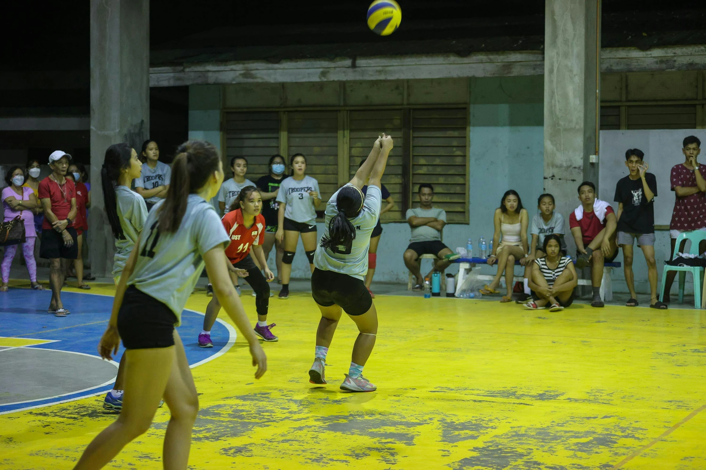 people watching a beach ball game play in a gym