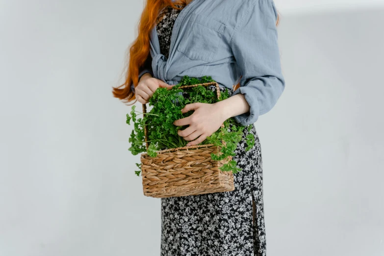 the woman is holding a basket full of herbs