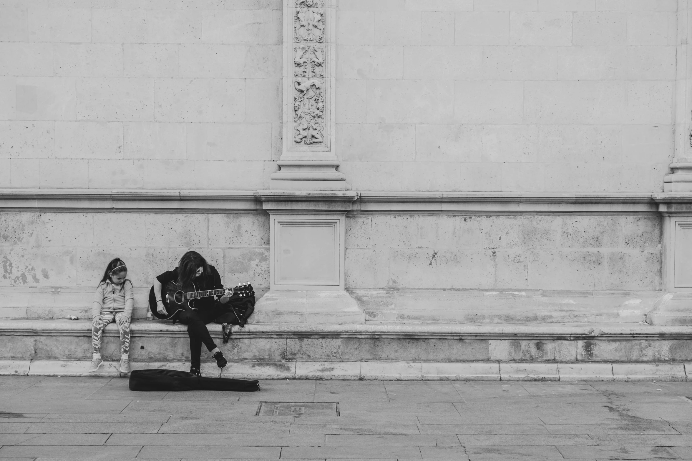 black and white pograph of two people sitting in front of a building