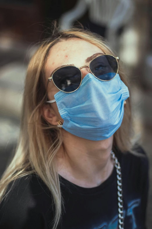 a woman with sunglasses and a mask on is wearing sunglasses