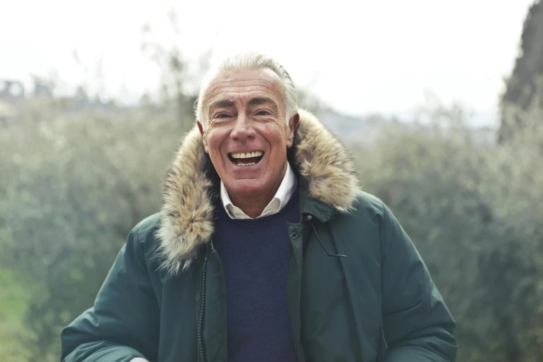 an older man is standing outside smiling