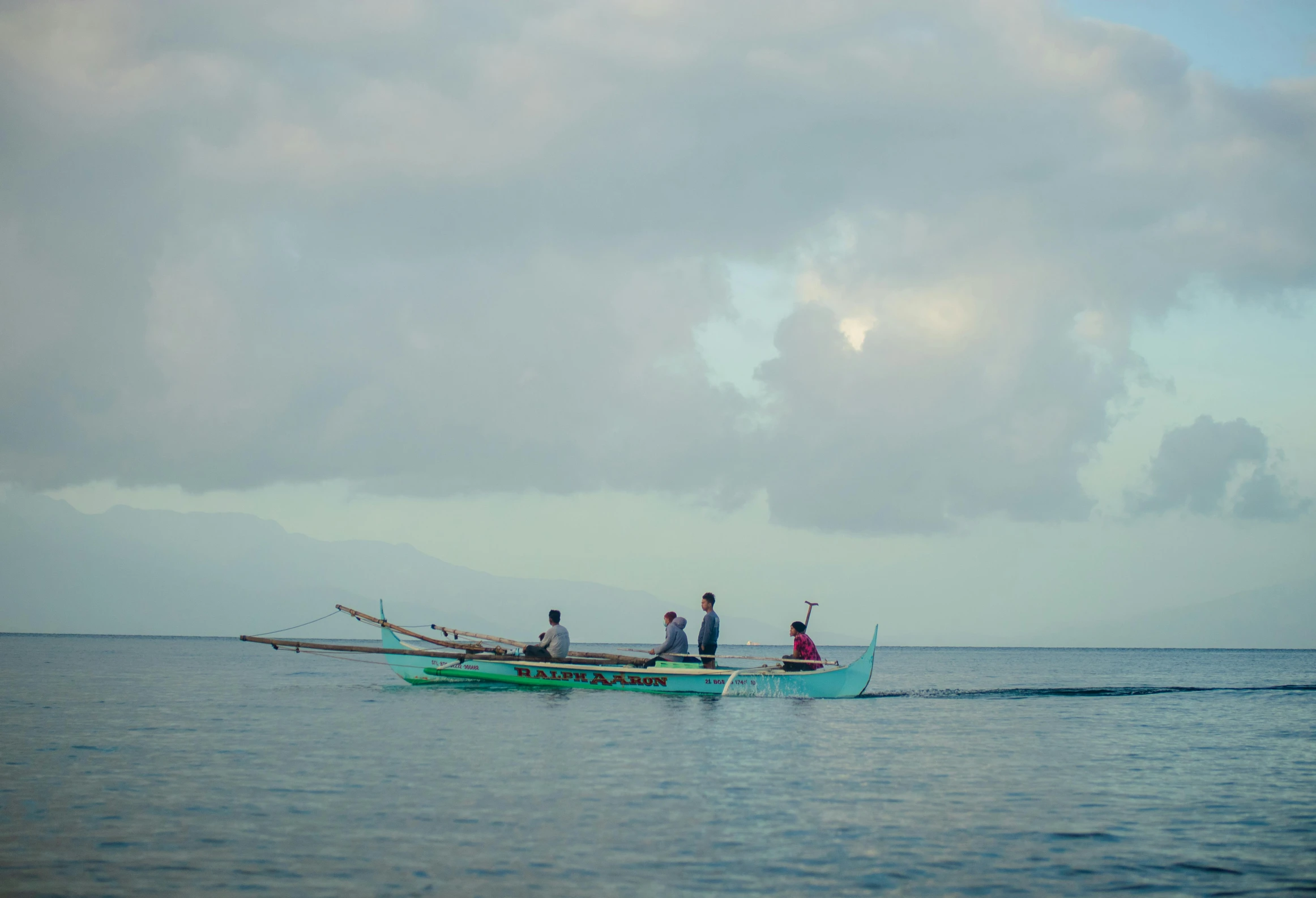 several people standing on the back of two small boats in the water