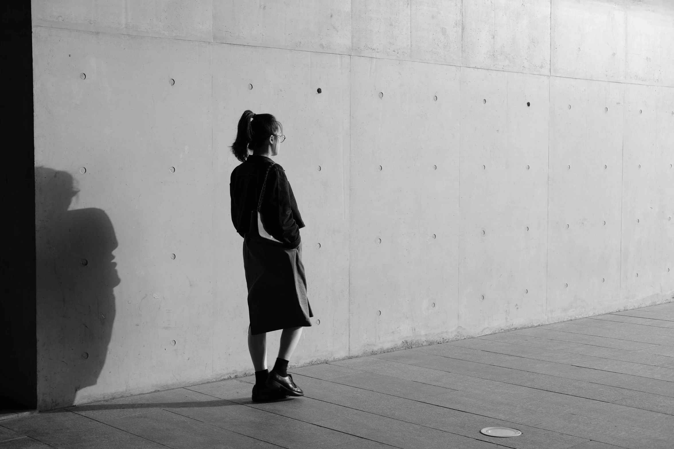 a woman standing next to a white wall