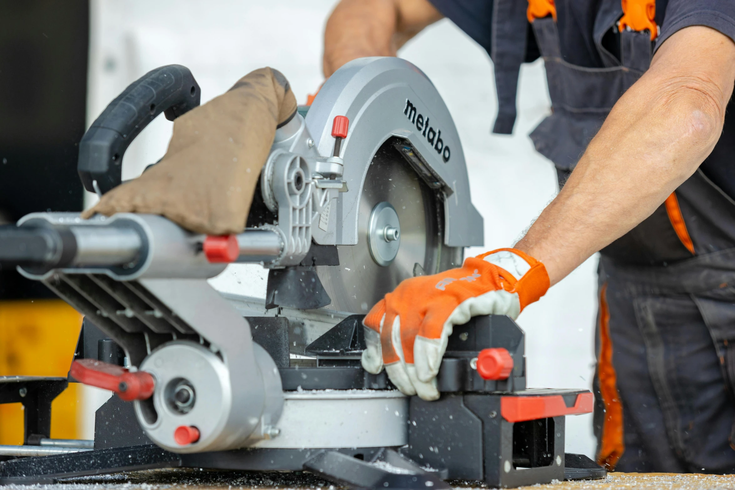 a man with orange gloves is holding onto a circular saw