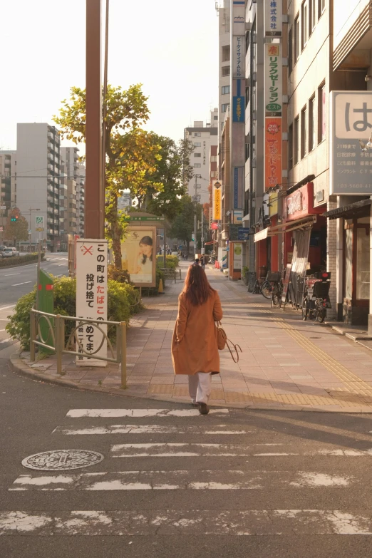 a woman walking across a cross walk holding an umbrella