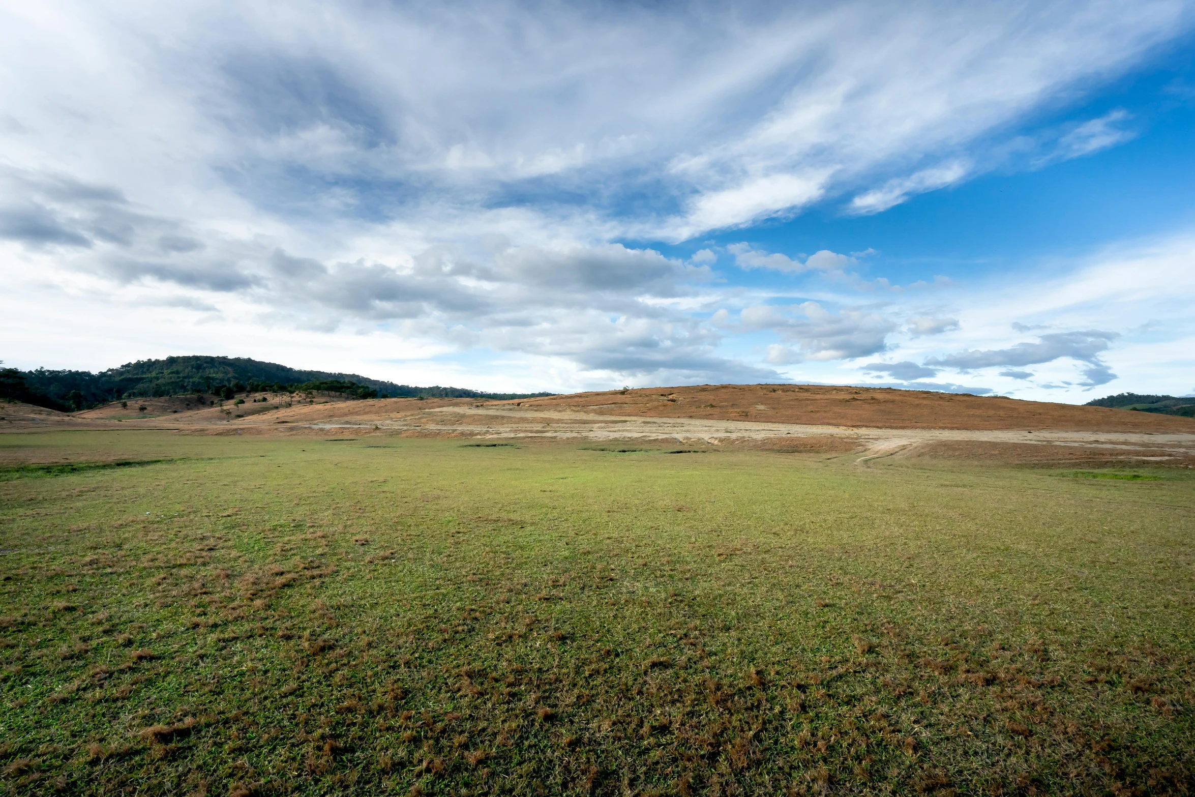 an empty grassy field with hills in the distance