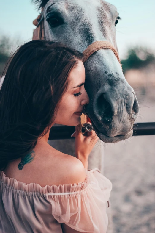 a girl in pink holding onto a horse near her nose