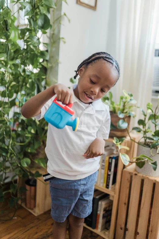 a girl standing on a hardwood floor with a blue toy in her hands