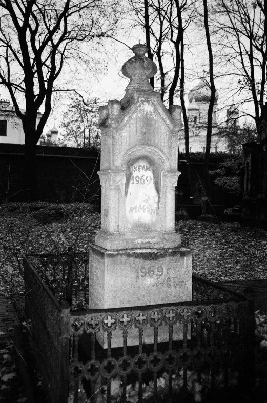 a cement monument sits in a cemetery with trees