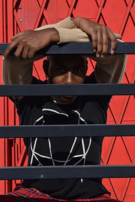 a man is sitting outside in front of the red wall