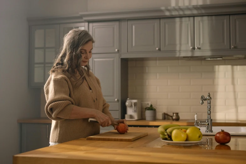 a woman in a kitchen  apples on top of a  board