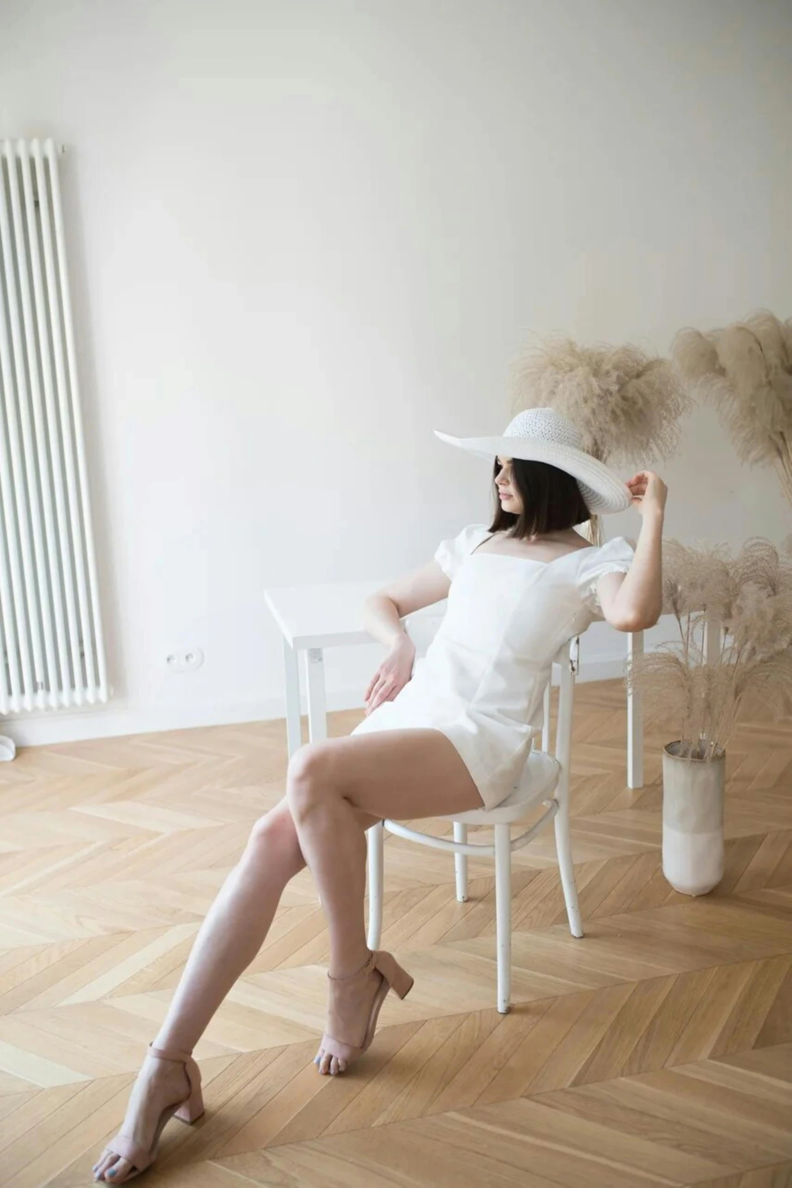 a woman sits on a white chair with her legs crossed
