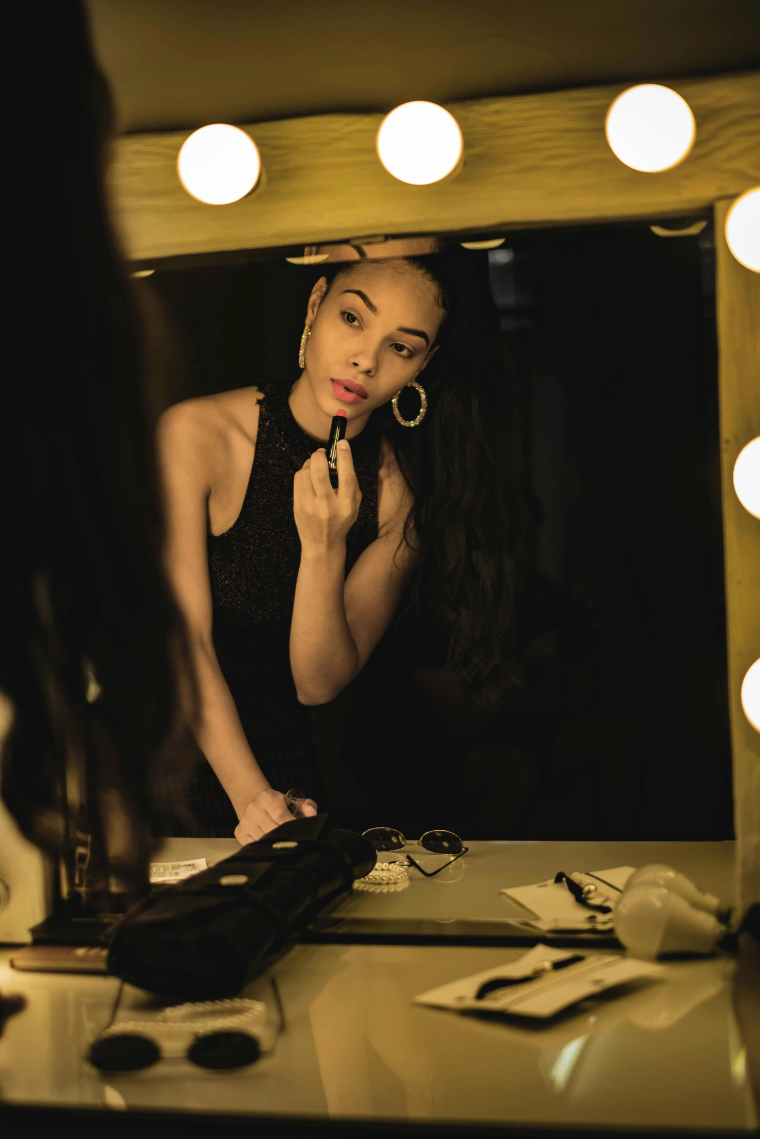 woman in front of vanity mirror with lights on the wall