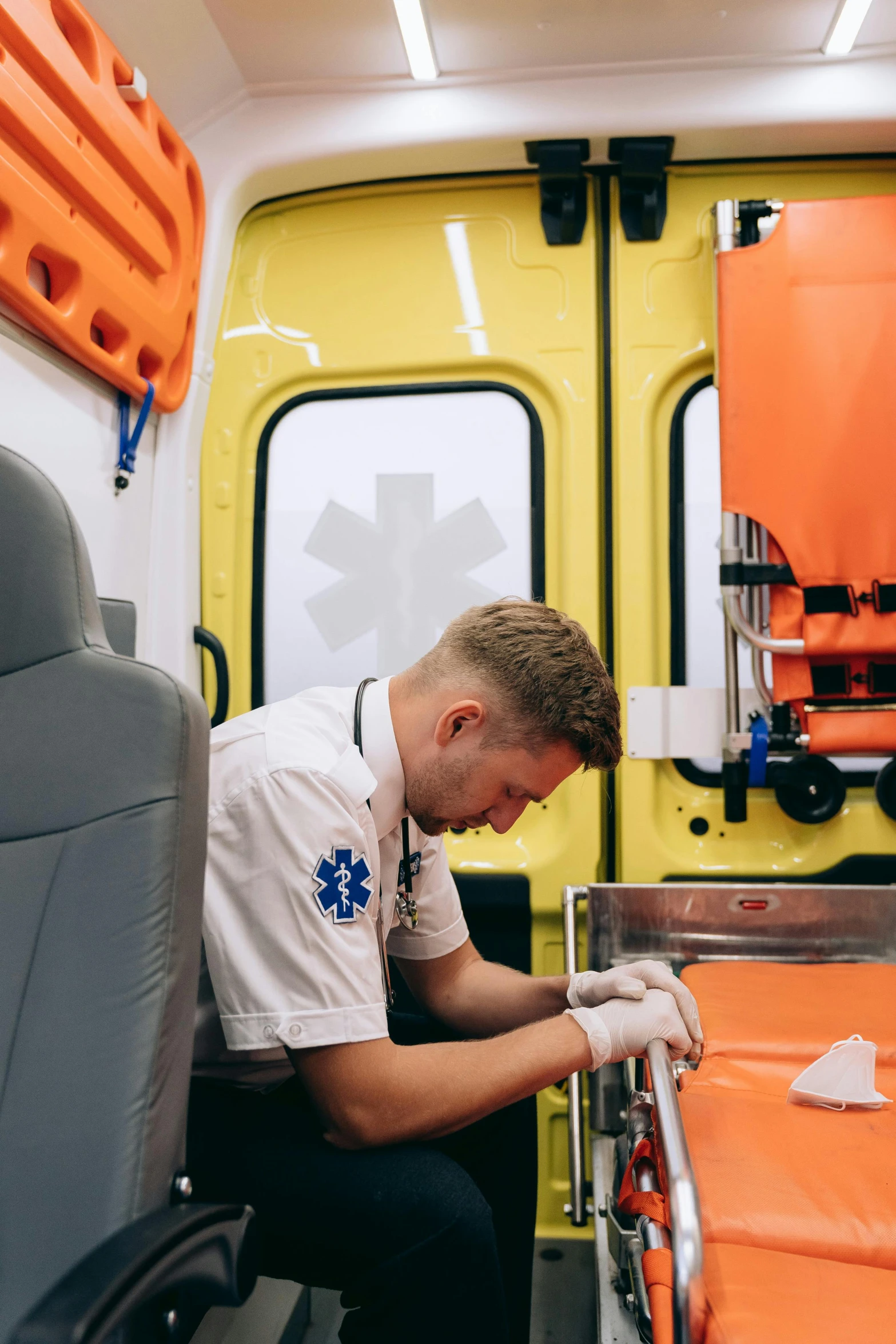 a man in an ambulance examines an orange hospital bed