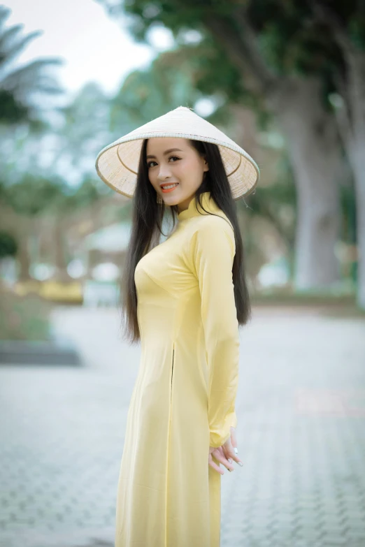 a smiling woman wearing a yellow dress and white hat