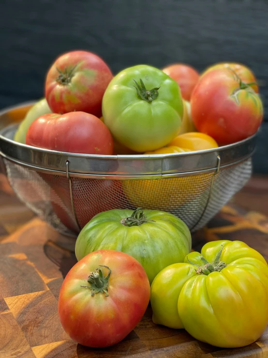 a bowl full of tomatoes and an apple in front