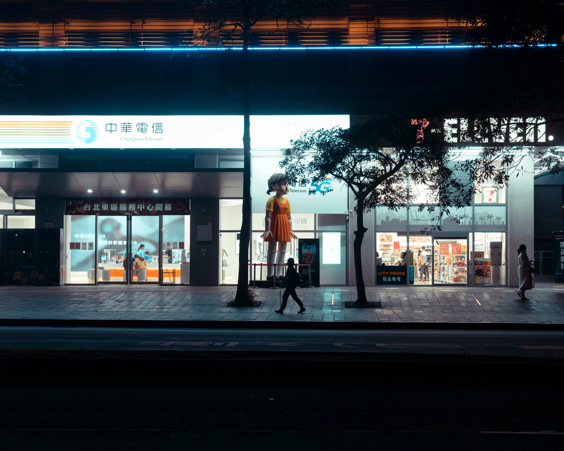 a woman with a suitcase walking past a building at night