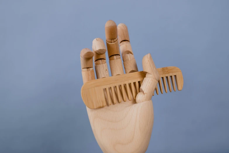 a wood cut out sculpture that looks like a hand with bamboo toothbrushes stuck in it