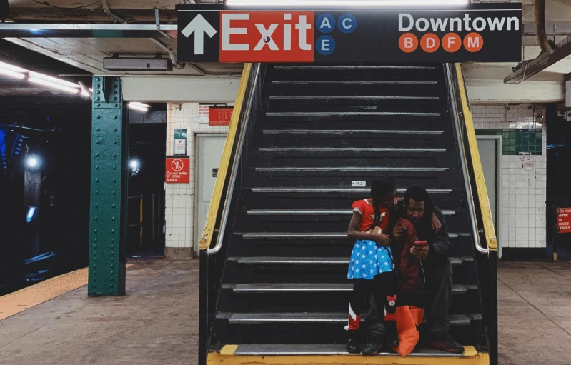 a group of people stand on the steps of a subway station